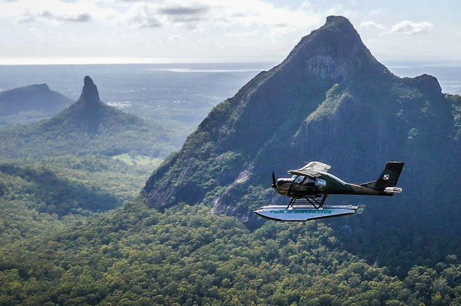 Seaplane flying with the majestic glass house mountains in the background