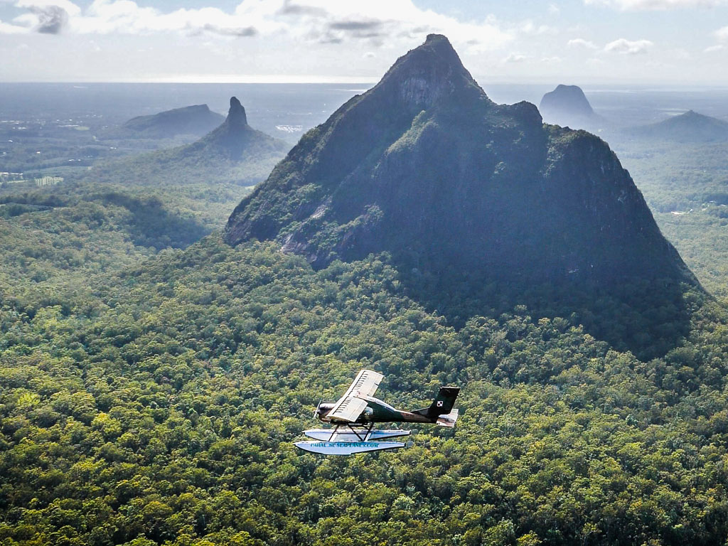 Wilga Warbird Seaplane flying in front of Glasshouse Mountains at the Sunshine Coast