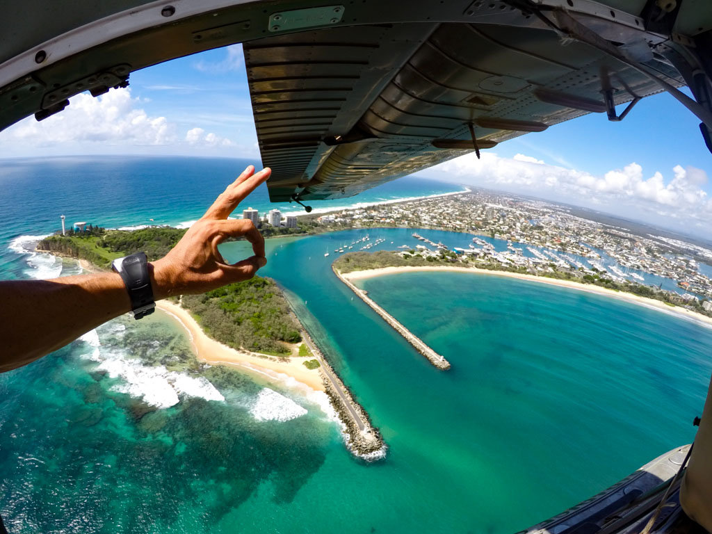 Hand with OK symbol with wing of seaplane and coastal views Mooloolaba